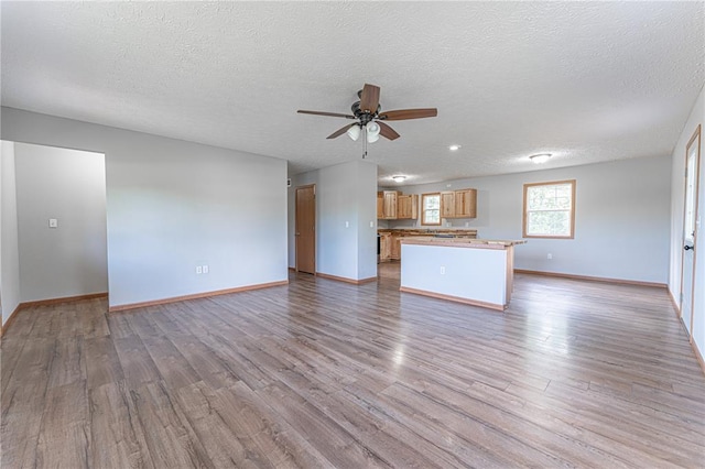 26805 Stephanie Ln, Laquey, MO 65534 - unfurnished living room featuring ceiling fan, baseboards, wood finished floors, and a textured ceiling