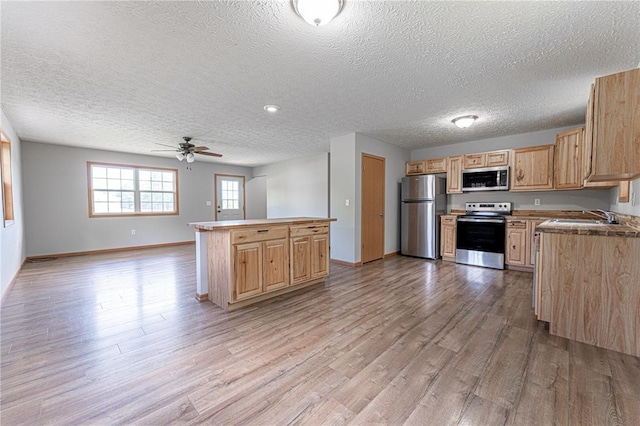 26805 Stephanie Ln, Laquey, MO 65534 - kitchen featuring stainless steel appliances, open floor plan, light brown cabinetry, light wood-style flooring, and a textured ceiling