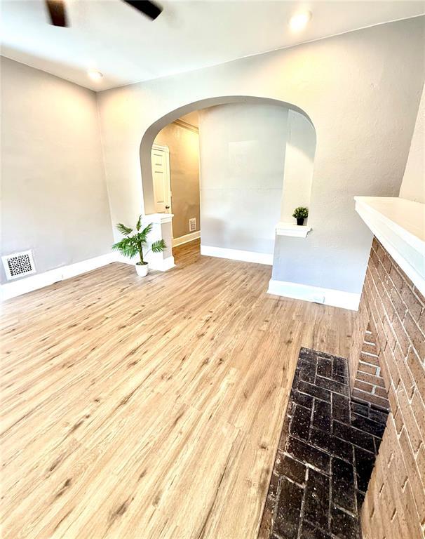unfurnished room featuring wood finished floors, baseboards, and arched walkways