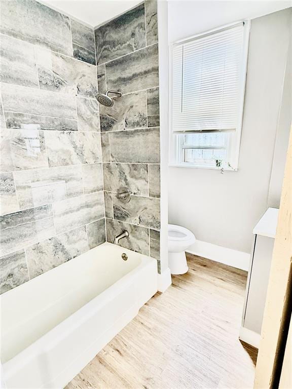 full bath with toilet, wood finished floors, baseboards, and shower / bathtub combination