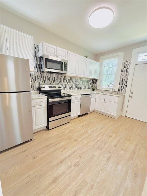 kitchen with stainless steel appliances, light countertops, white cabinets, and decorative backsplash