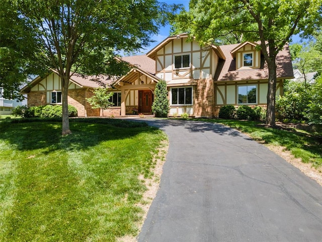 1807 Brookcreek Ln, Kirkwood, MO 63122 - tudor home featuring roof with shingles, a front lawn, driveway, and brick siding