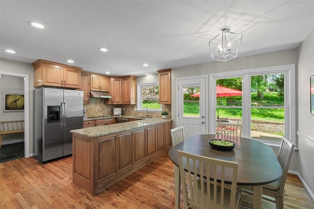 1807 Brookcreek Ln, Kirkwood, MO 63122 - kitchen with stainless steel refrigerator with ice dispenser, a sink, under cabinet range hood, light wood-style floors, and light stone countertops