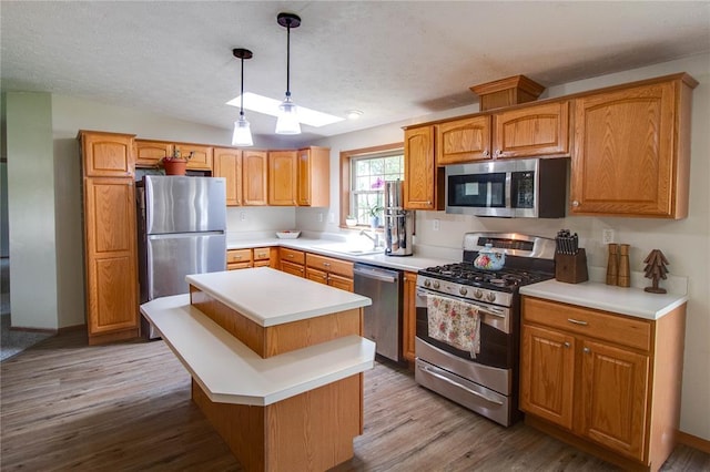 27467 Spruce Rd, Greenfield, IL 62044 - kitchen with appliances with stainless steel finishes, wood finished floors, a center island, light countertops, and decorative light fixtures