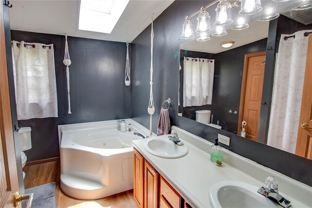 27467 Spruce Rd, Greenfield, IL 62044 - full bath with toilet, wood finished floors, a skylight, a whirlpool tub, and double vanity