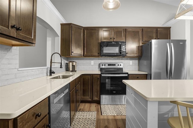 kitchen with stainless steel appliances, a sink, dark brown cabinetry, light wood-style floors, and light countertops
