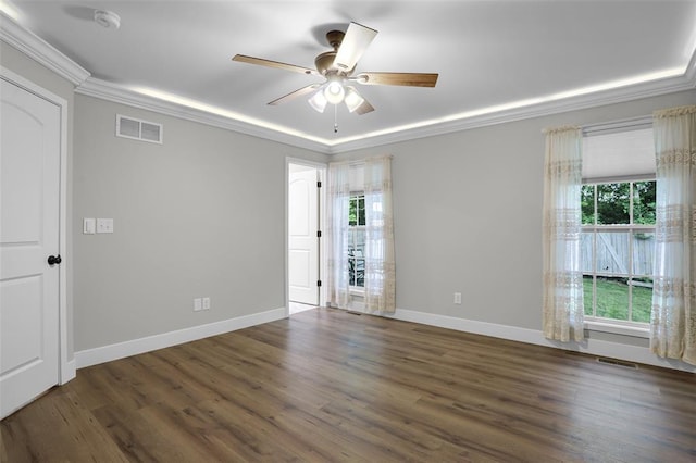 empty room featuring ornamental molding, healthy amount of natural light, wood finished floors, a ceiling fan, and a smoke detector