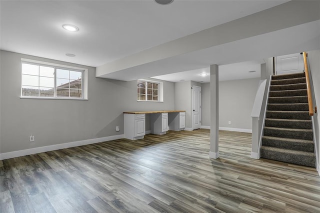 basement with baseboards, wood finished floors, and stairway