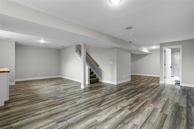 finished below grade area featuring dark wood-style flooring, baseboards, and stairs