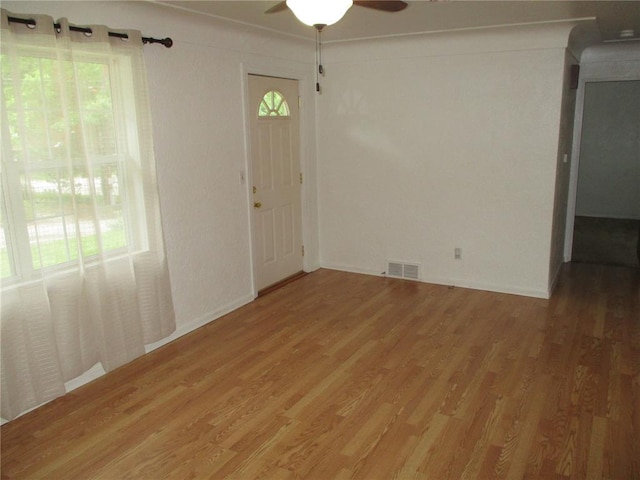 empty room with light wood finished floors and a ceiling fan