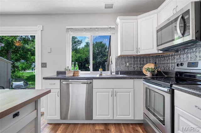 193 Harbor View Dr, Lake St Louis, MO 63367 - kitchen featuring stainless steel appliances, dark countertops, white cabinetry, and tasteful backsplash