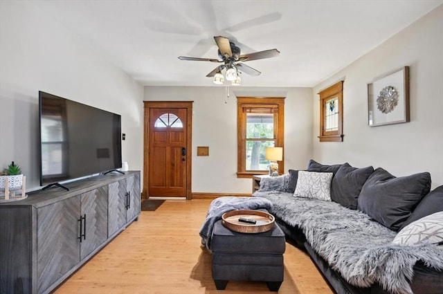 living area with a ceiling fan, light wood-style floors, and baseboards