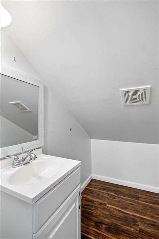 bathroom with lofted ceiling, wood finished floors, baseboards, and vanity