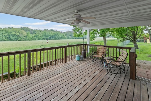 wooden terrace featuring a ceiling fan and a lawn