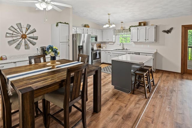 dining space featuring a chandelier, light wood finished floors, ceiling fan, and lofted ceiling