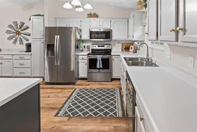 kitchen featuring appliances with stainless steel finishes, a sink, light wood finished floors, light countertops, and white cabinets