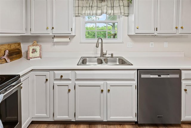 kitchen with appliances with stainless steel finishes, a sink, light countertops, and white cabinets