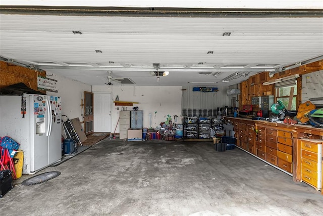 garage featuring white refrigerator with ice dispenser, a garage door opener, and a workshop area