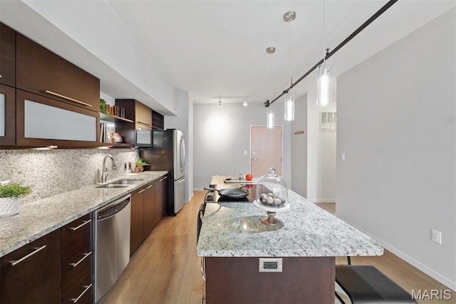 915 Olive St Unit 910, Saint Louis, MO 63101 - kitchen featuring appliances with stainless steel finishes, a breakfast bar area, light wood finished floors, tasteful backsplash, and dark brown cabinets