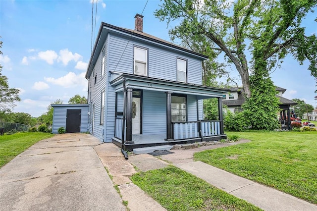 american foursquare style home with covered porch, a front yard, a chimney, and driveway