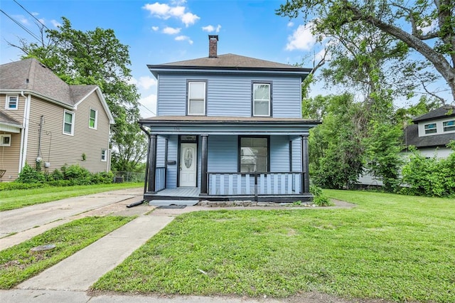 american foursquare style home with covered porch, a chimney, and a front lawn