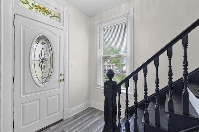 entryway featuring wood finished floors, baseboards, and stairs