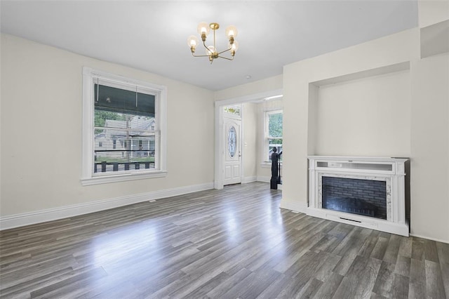 unfurnished living room featuring a chandelier, wood finished floors, baseboards, and a fireplace