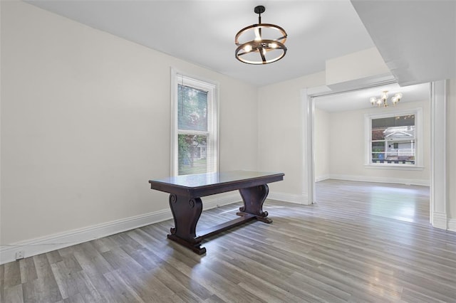 unfurnished dining area with a chandelier, light wood-style floors, and baseboards