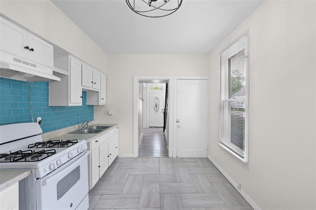 kitchen with white range with gas cooktop, a sink, baseboards, and light countertops