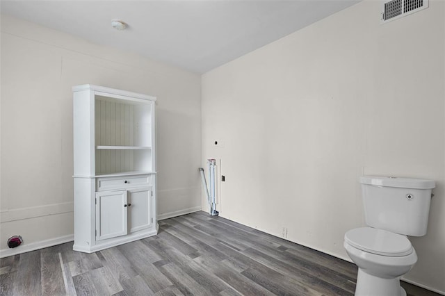 empty room featuring wood finished floors, a smoke detector, and baseboards