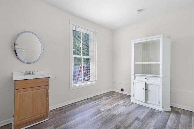 unfurnished dining area featuring wood finished floors, a sink, and baseboards