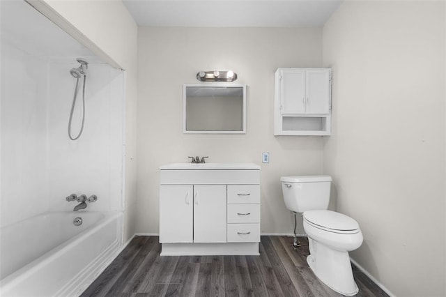 bathroom with wood finished floors, toilet, vanity, shower / tub combination, and baseboards