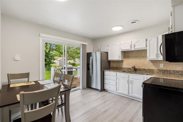 kitchen featuring appliances with stainless steel finishes, a sink, white cabinets, and backsplash