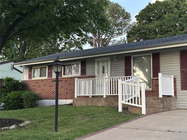 view of front facade featuring brick siding, a front lawn, and covered porch