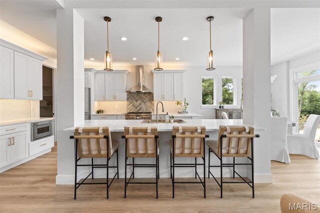 401 Rayburn Ave, Sunset Hills, MO 63127 - kitchen with wall chimney exhaust hood, a sink, decorative backsplash, light countertops, and white cabinetry
