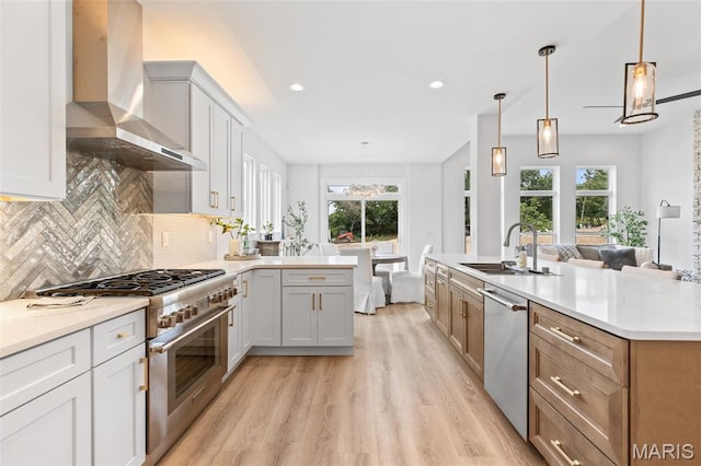 401 Rayburn Ave, Sunset Hills, MO 63127 - kitchen featuring wall chimney exhaust hood, stainless steel appliances, a sink, light wood finished floors, and tasteful backsplash