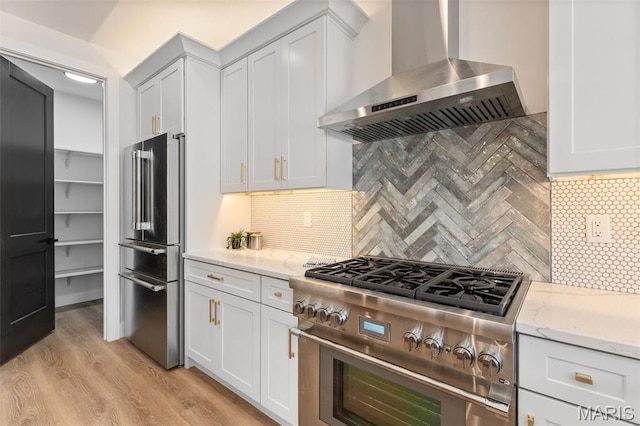 401 Rayburn Ave, Sunset Hills, MO 63127 - kitchen with wall chimney exhaust hood, high end appliances, light stone countertops, light wood finished floors, and tasteful backsplash
