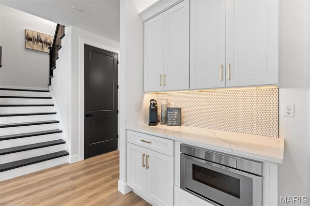 401 Rayburn Ave, Sunset Hills, MO 63127 - kitchen featuring light wood-style floors, light stone counters, backsplash, wall oven, and stainless steel microwave