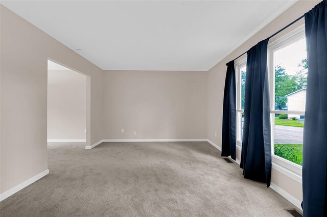 spare room with light carpet and baseboards