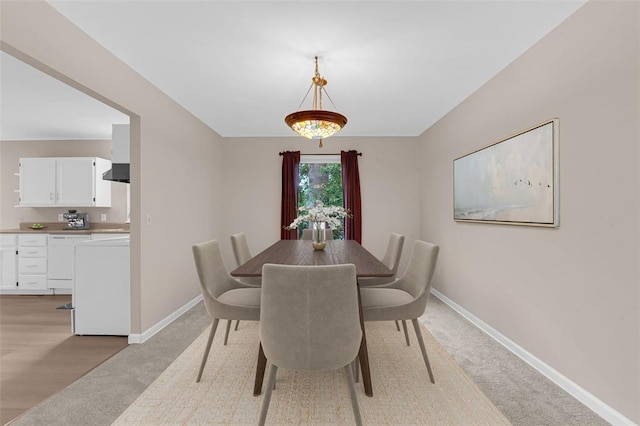 dining room with baseboards and light carpet