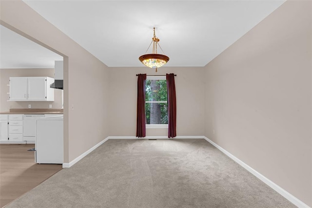 empty room featuring baseboards and light carpet