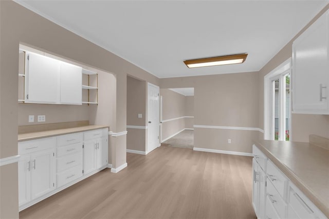 kitchen with light wood finished floors, white cabinetry, open shelves, light countertops, and baseboards