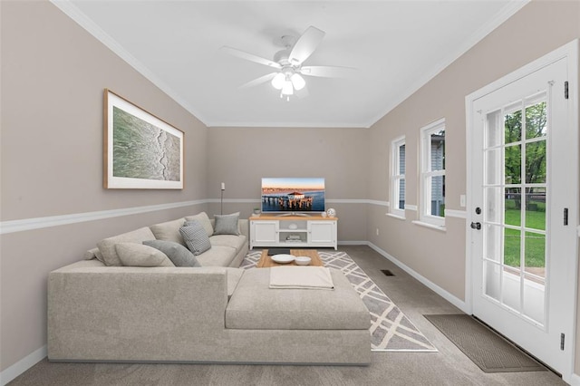 carpeted living area with a ceiling fan, baseboards, and ornamental molding