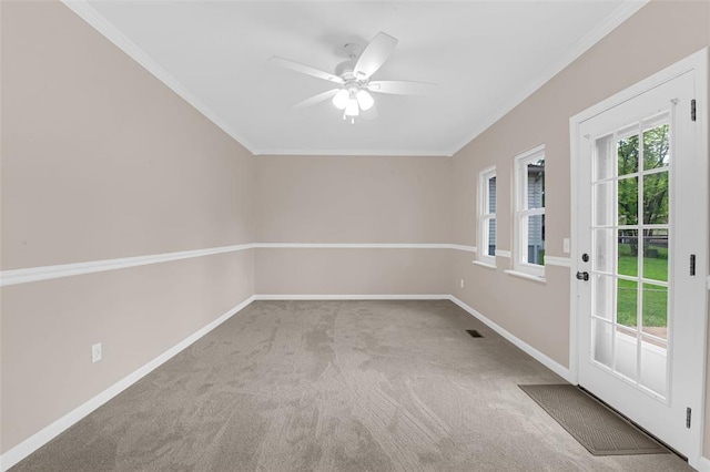 carpeted spare room featuring a ceiling fan, baseboards, and crown molding