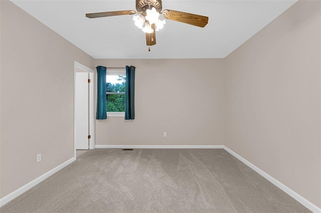 carpeted spare room with a ceiling fan and baseboards
