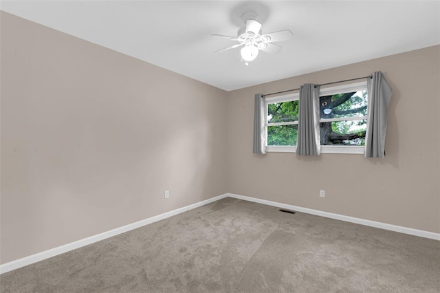 empty room featuring carpet flooring, baseboards, and a ceiling fan