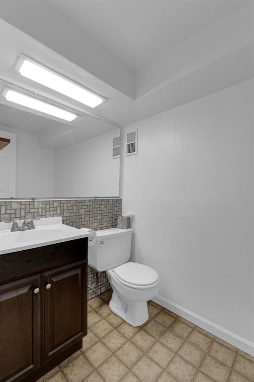 half bathroom featuring toilet, vanity, and tasteful backsplash