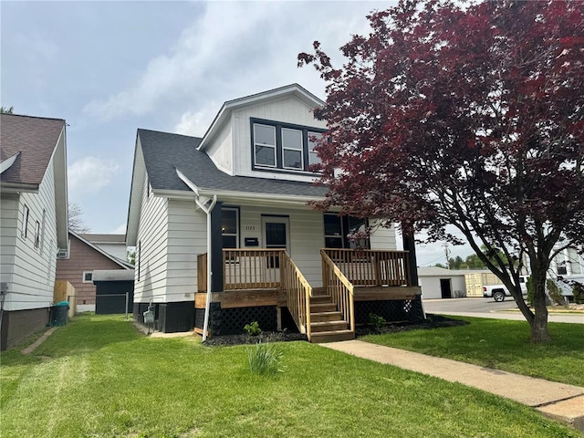 view of front of home with a porch, a front yard, and a shingled roof