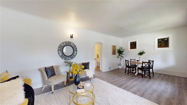 living room featuring arched walkways, wood finished floors, and baseboards