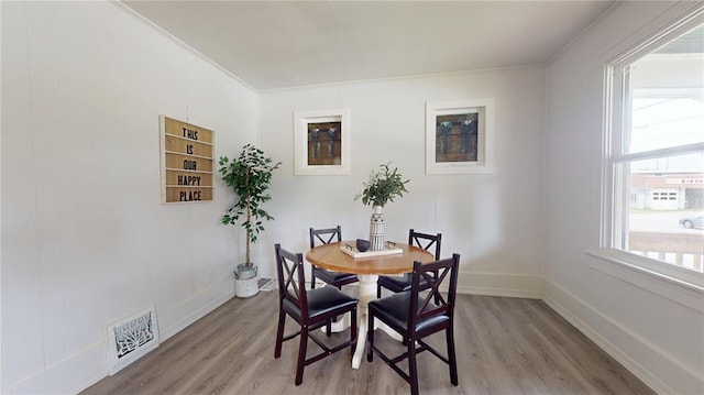 dining room with wood finished floors, crown molding, and baseboards